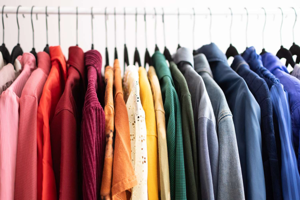 Color coded rack of button up shirts ranging from pink, red, green, to blue going left to right.