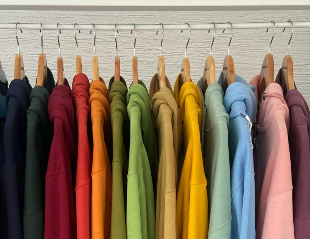 Hoodies on a rack forming a rainbow of colors.
