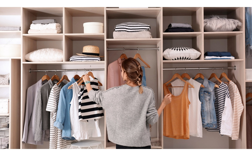 A woman organizing a closet with many cubby holes and areas to hang clothing.