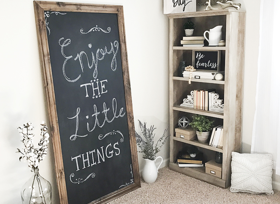A large chalkboard on a wall perpendicular to the wall a large bookcase is on.