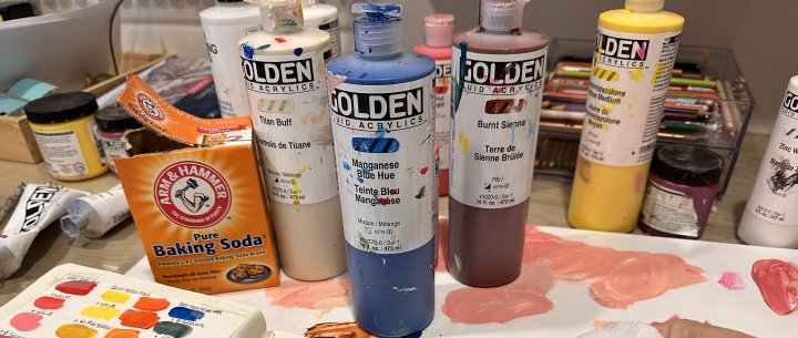 Baking soda opened next to old paint container tubes.