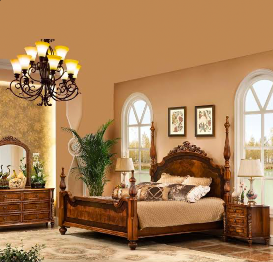 Classic wooden bedroom with ornate bed, chandelier, and elegant decor.