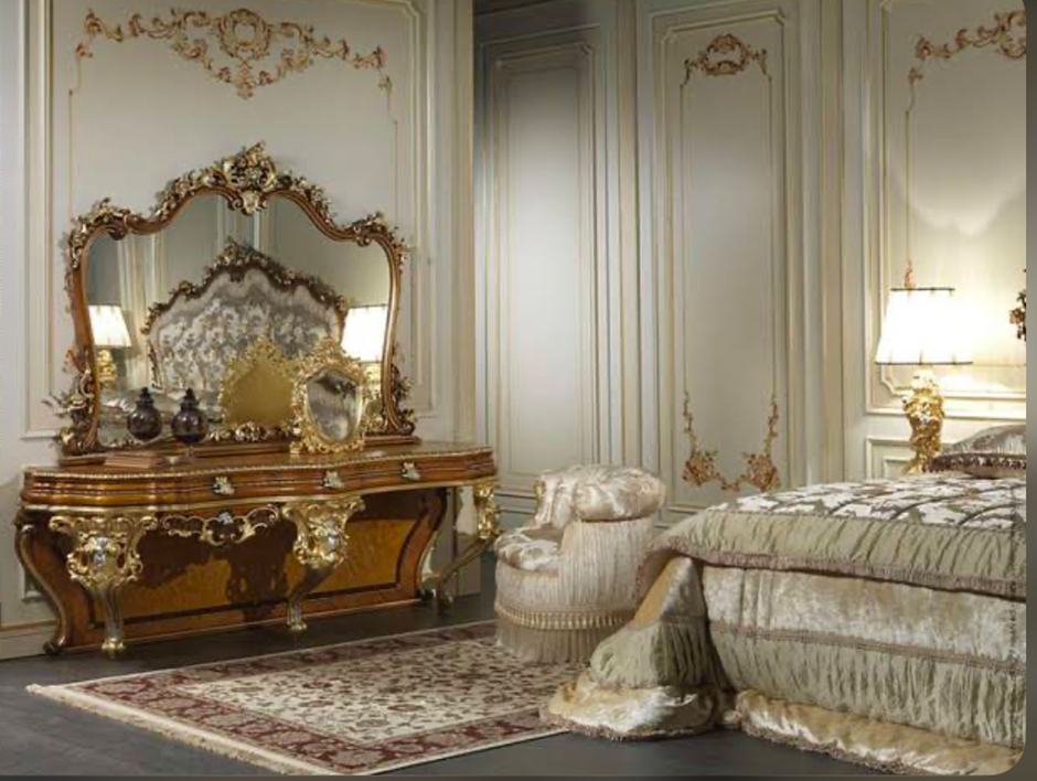 Luxurious vintage bedroom with gold-trimmed dresser and ornate mirror.