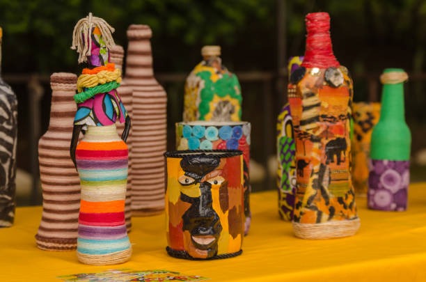upcycled glass bottles decorated with colorful yarn paint and mixed media designs on a craft table
