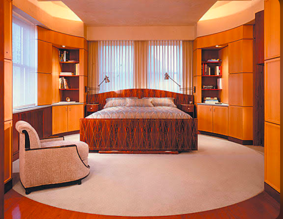 Modern curved wood bedroom with built-in shelves and cozy chair.