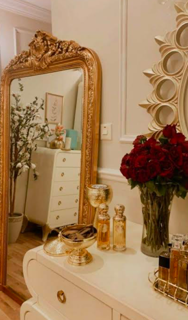 Elegant vanity with a golden-framed mirror, red roses, and perfume bottles