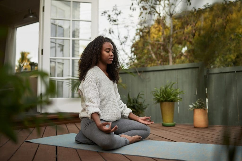 Woman meditating peacefully on a patio, practicing mindfulness for mental clarity and relaxation.