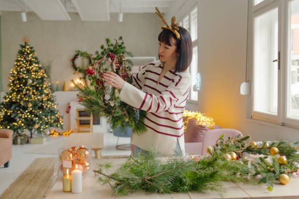 A woman decorating with plants for the holidays in a living room.