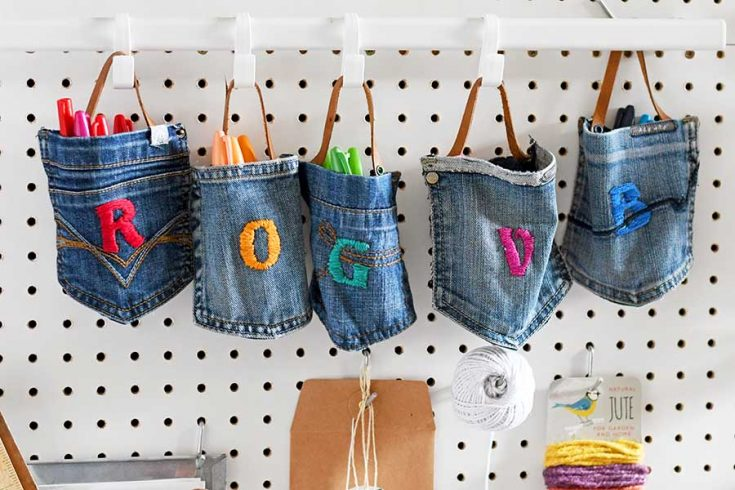 Five jeans pockets hung up by leather straps to hooks and being used as holders.