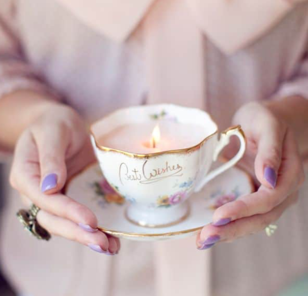 A woman holds a candle holder repurposed from a ceramic teacup