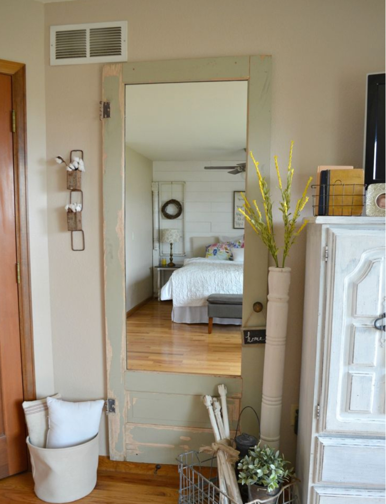 Tall mirror framed by an old painted door