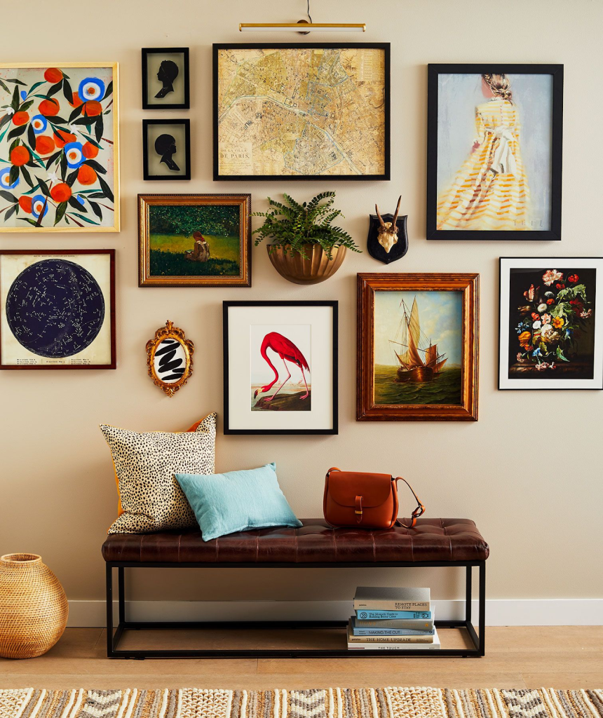 A wall turned into a gallery of different colorful framed photographs above a entry way seating bench.
