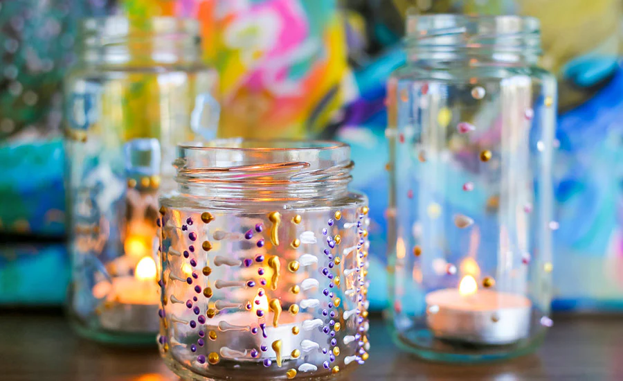 A jar with paint finishes being prepped to be used a a candle holder.