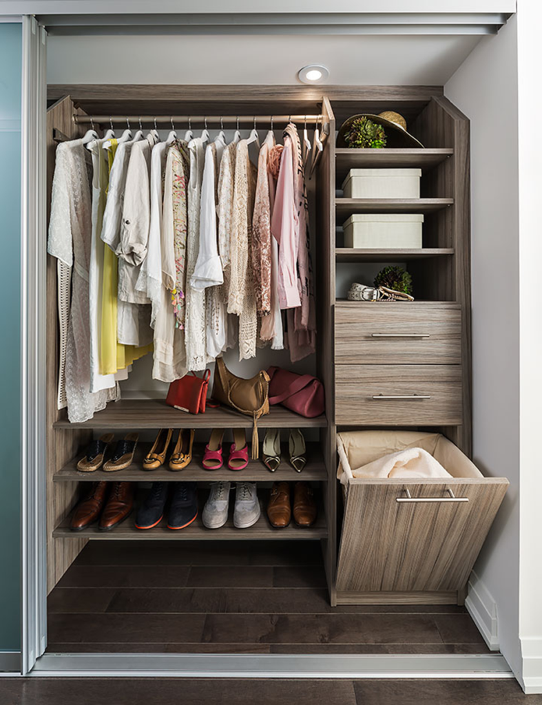 Modern wooden closet with neatly arranged clothes, shoes, and storage drawers