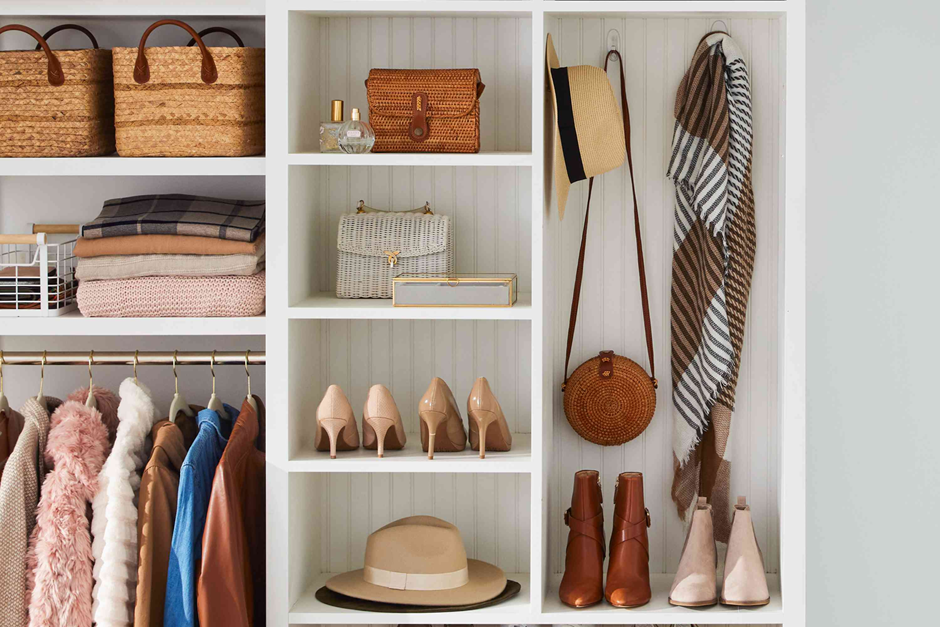 Stylish open closet with coats, shoes, hats, and woven storage baskets