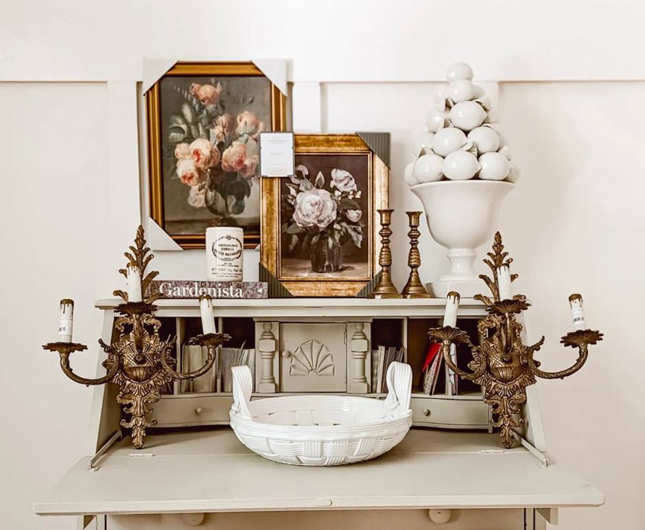 Vintage-inspired console table decorated with floral art, candlesticks, and antique accents