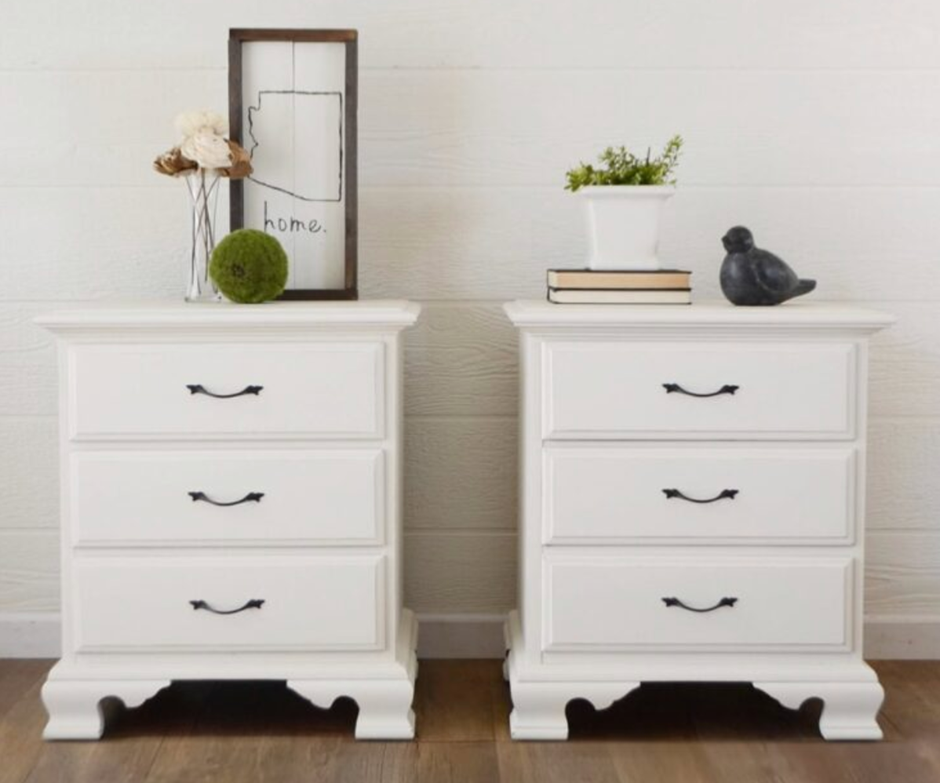 Pair of white farmhouse-style nightstands with decorative books and plants