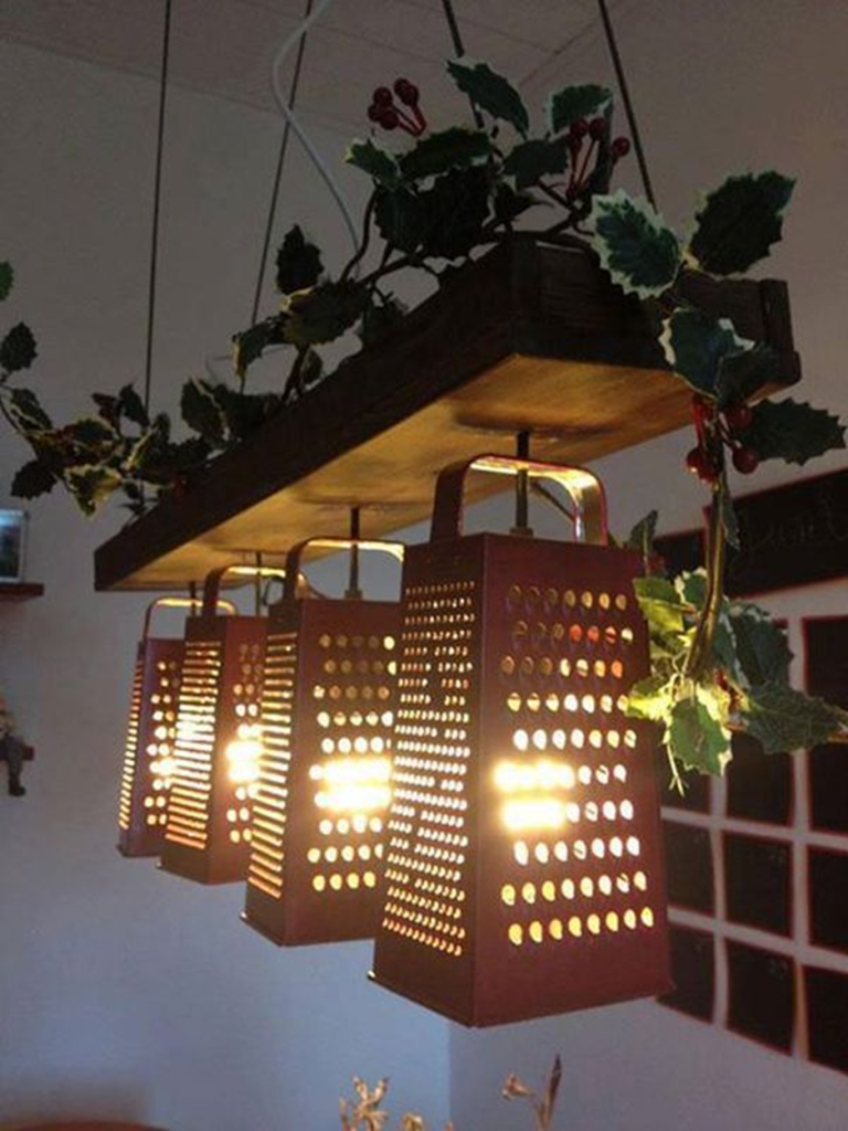Upcycled cheese graters turned into hanging pendant lights with warm glowing bulbs and decorative greenery