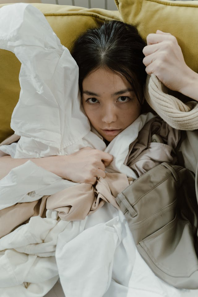 A woman covered in a pile of clothes.