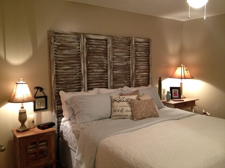 Farmhouse-style bedroom featuring a repurposed distressed shutter headboard behind a cozy bed with neutral bedding and warm lighting