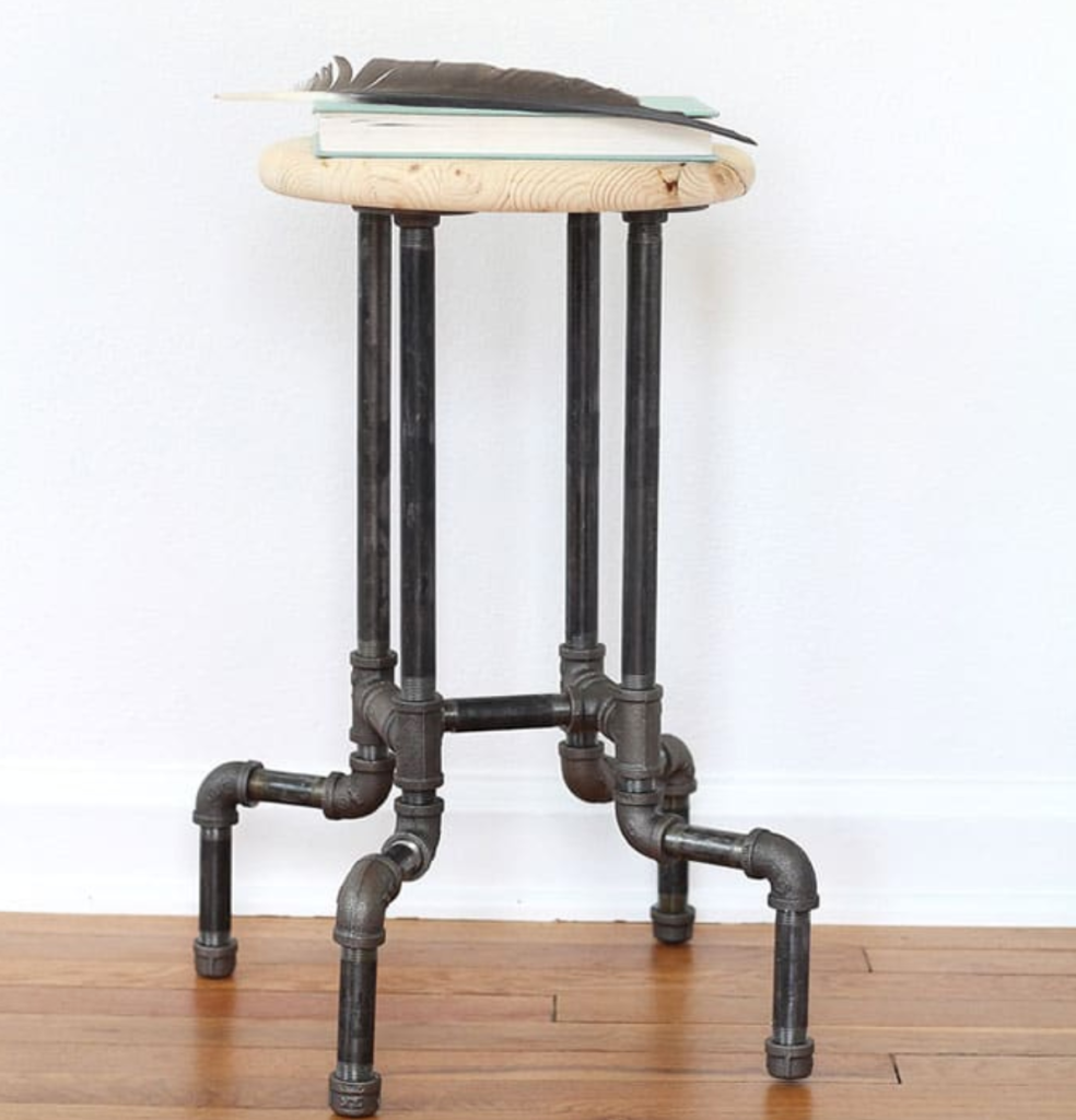 Industrial pipe stool with a wooden seat and black metal pipe legs.