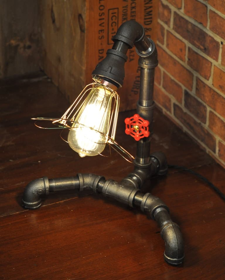 Industrial pipe table lamp with exposed Edison bulb and metal piping base.