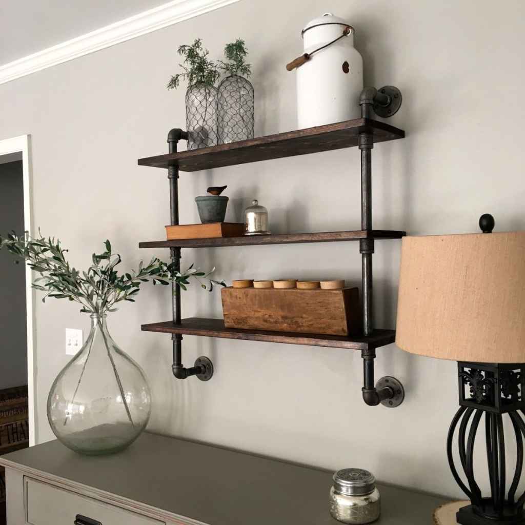 Wall-mounted industrial pipe shelving with wooden boards styled with home décor items.