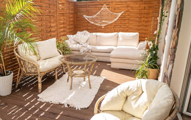 Outdoor seating area with wicker furniture, glass table, and wooden privacy wall