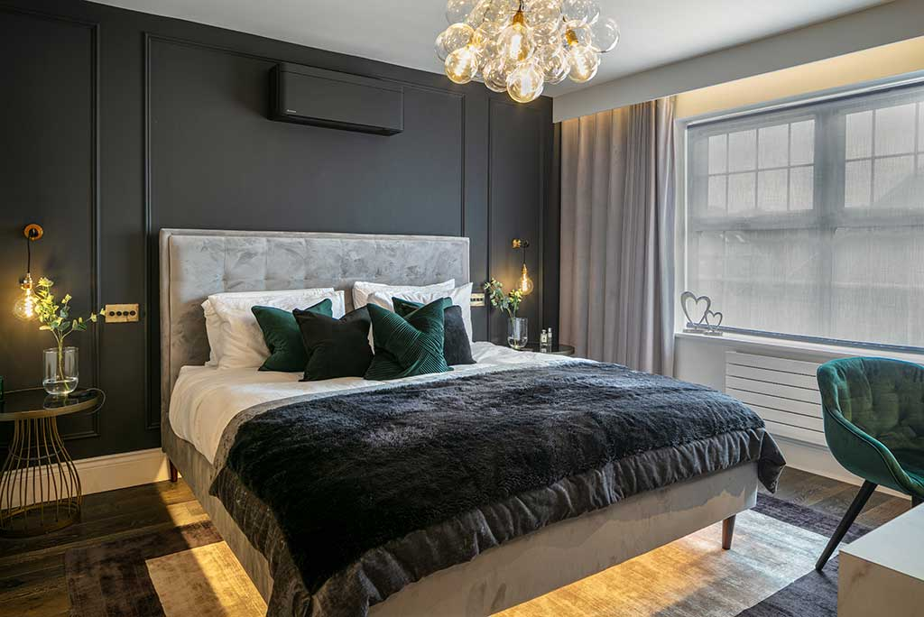 A bedroom made cozy with warm booth side table sconces and chandelier lighting.