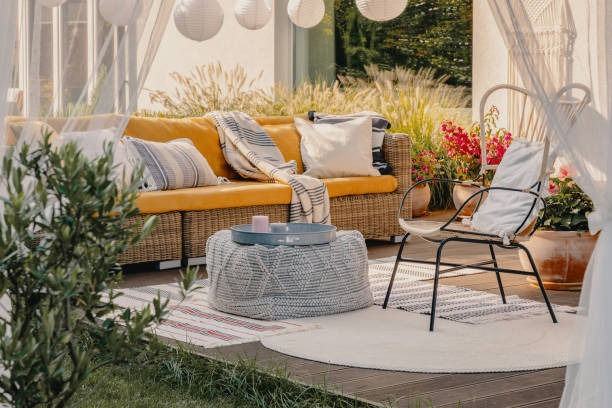 Outdoor patio with rattan sofa, white cushions, and soft neutral décor accents