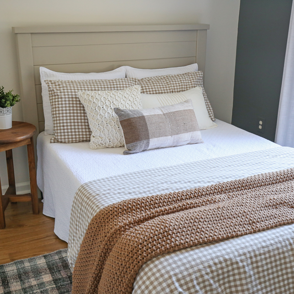 A close up of a bed in a bedroom that is layered with a few bedding sets.