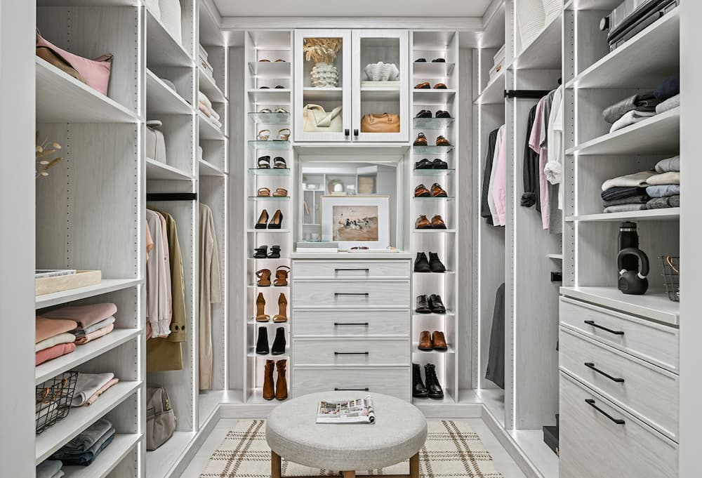 A beautiful lit built-in closet system with shoe racks.