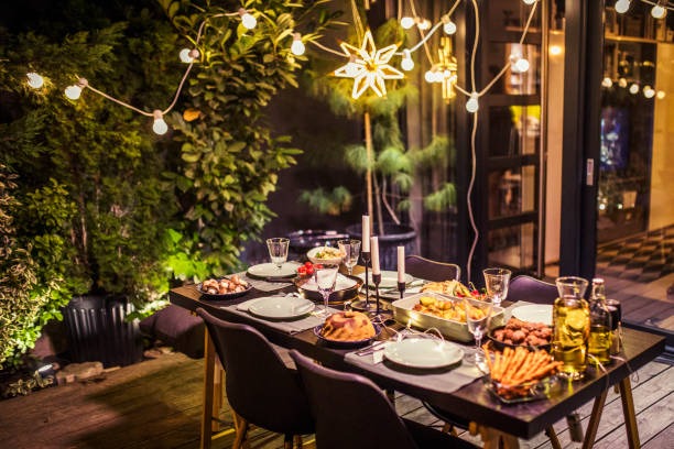 Outdoor dining table decorated with lights, candles, and a full dinner spread