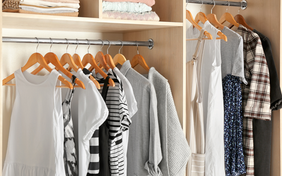 Neatly organized wardrobe with clothes hanging on wooden hangers and folded items on shelves