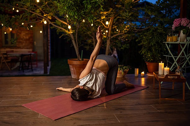 Woman practicing yoga on a patio at sunset with warm outdoor lighting