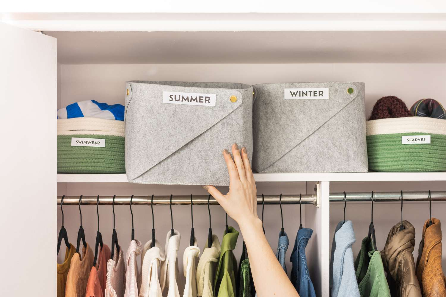 Labeled fabric storage bins for summer and winter clothes on an organized closet shelf
