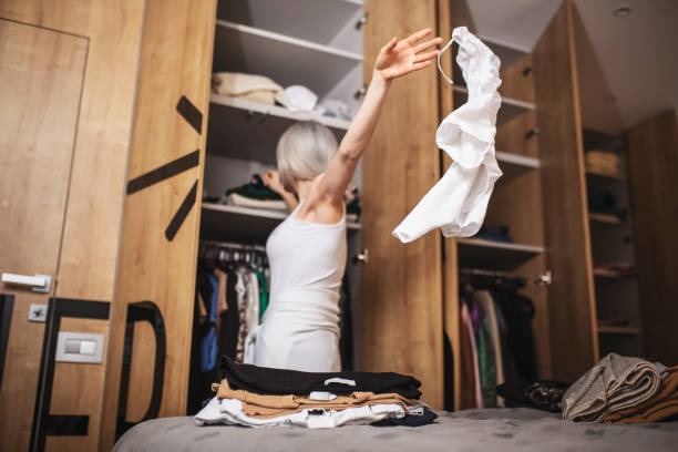 Woman sorting and organizing clothes from a wardrobe during closet decluttering