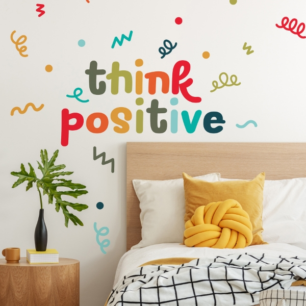 Think positive wall decal with colorful lettering above modern bedroom bed