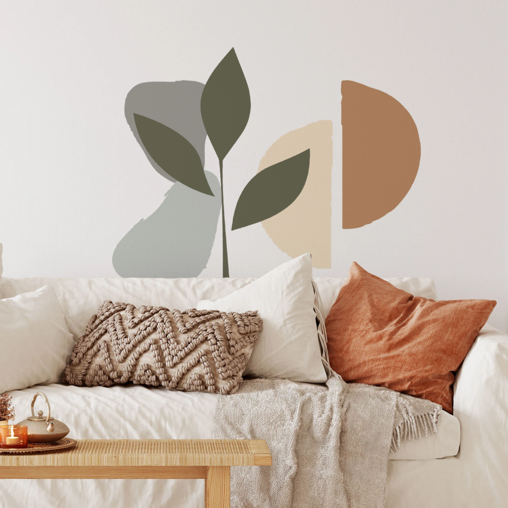 Abstract botanical wall mural with neutral shapes above cozy living room sofa