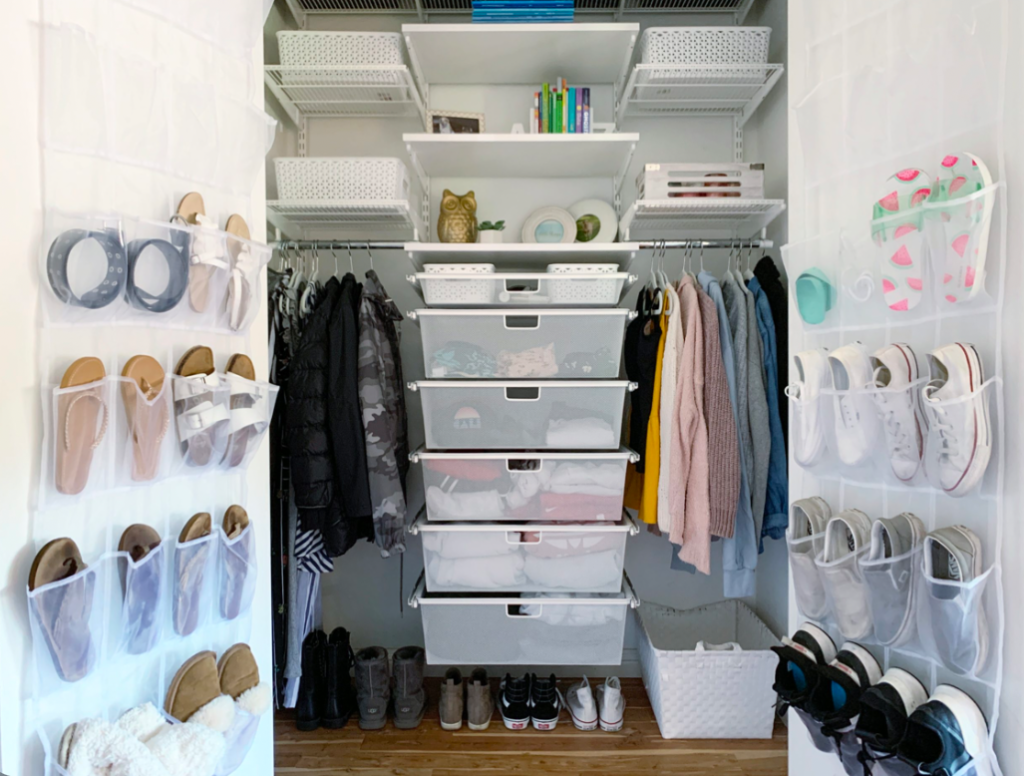 Small walk-in closet organization with hanging clothes, shoe storage, labeled drawers, and wall-mounted racks