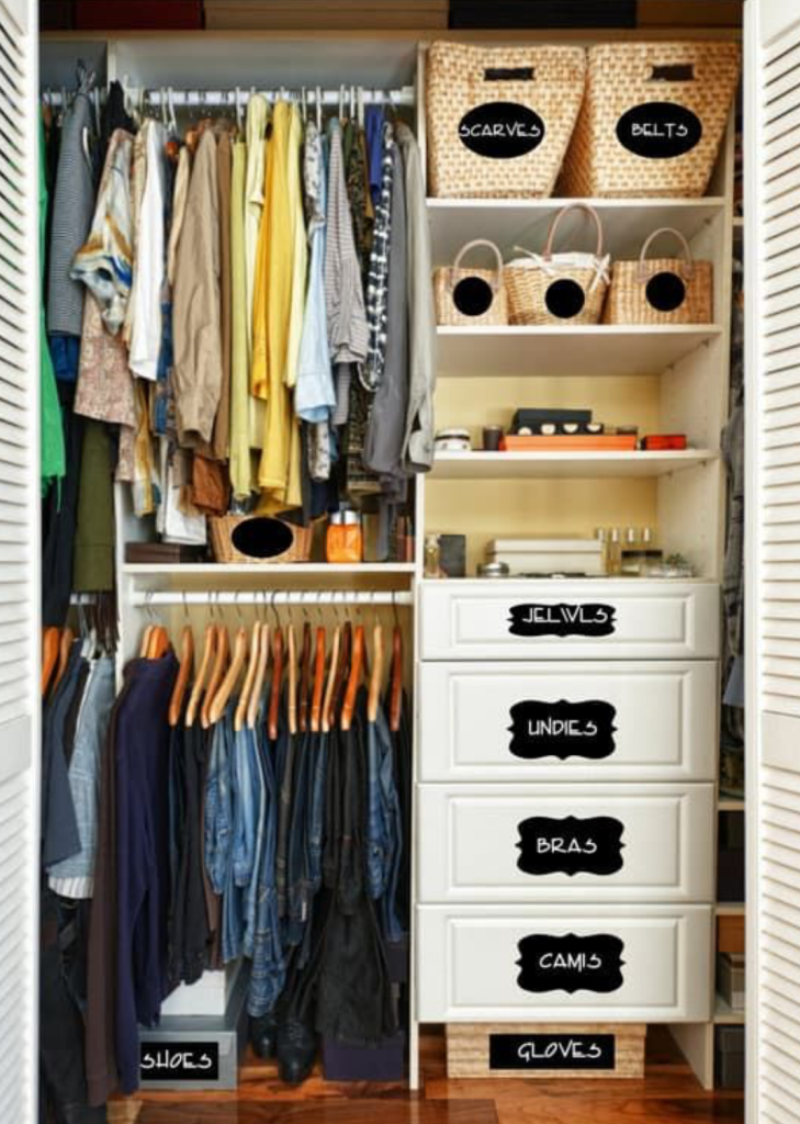 Well-organized wardrobe with labeled baskets and drawers for jeans, underwear, bras, camisoles, scarves, and belts