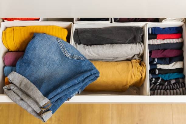 Drawer organizers holding folded jeans, shirts, and sweaters for tidy closet storage