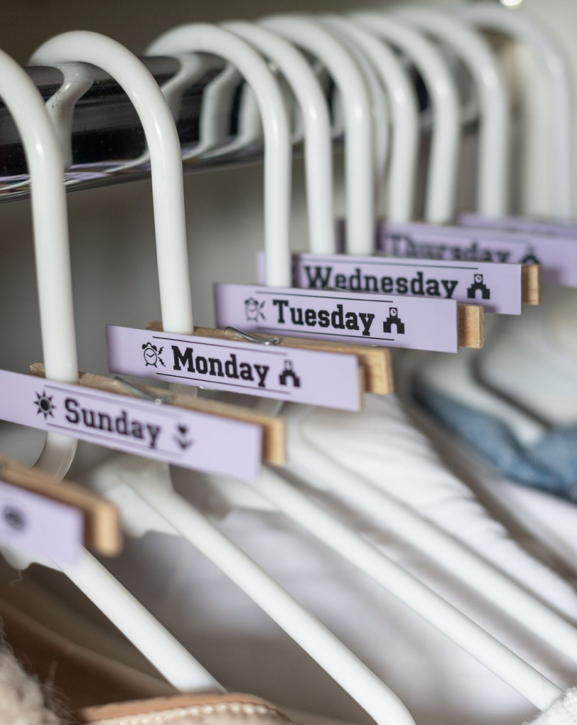 Closet hanger dividers labeled by days of the week for organizing outfits from Sunday to Saturday