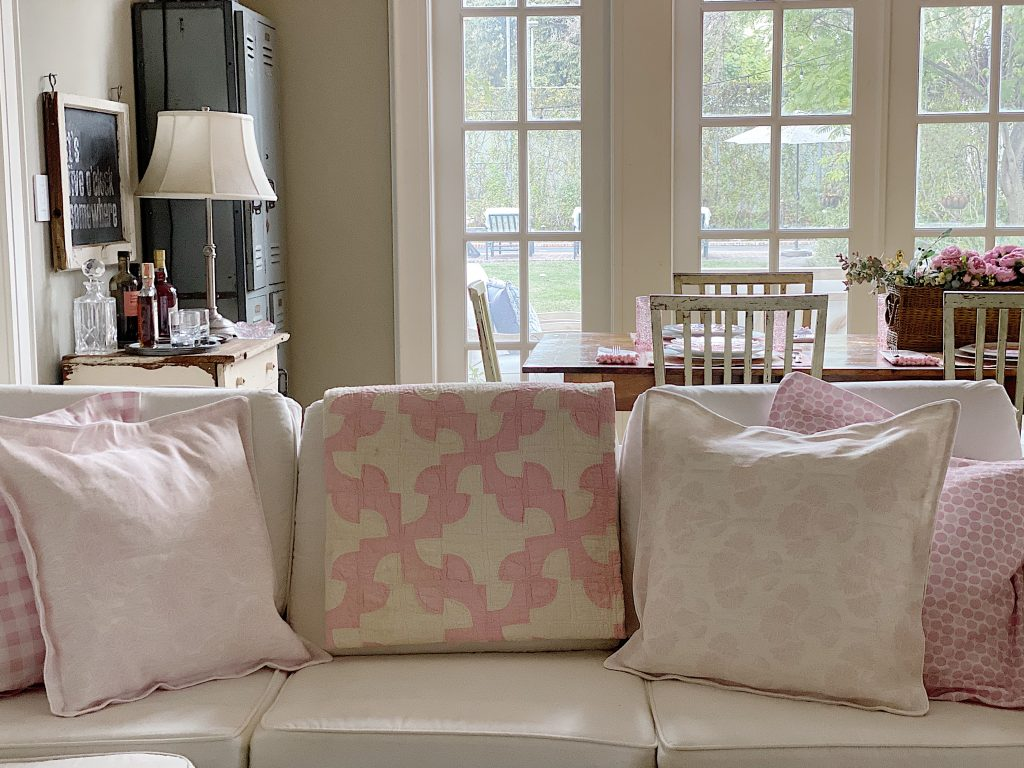 Cozy farmhouse living room with pastel throw pillows and rustic dining area view