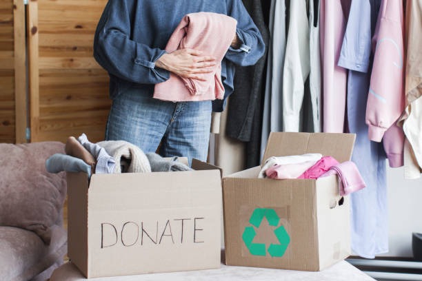 Sorting clothes into donate and recycle boxes during a closet organization session