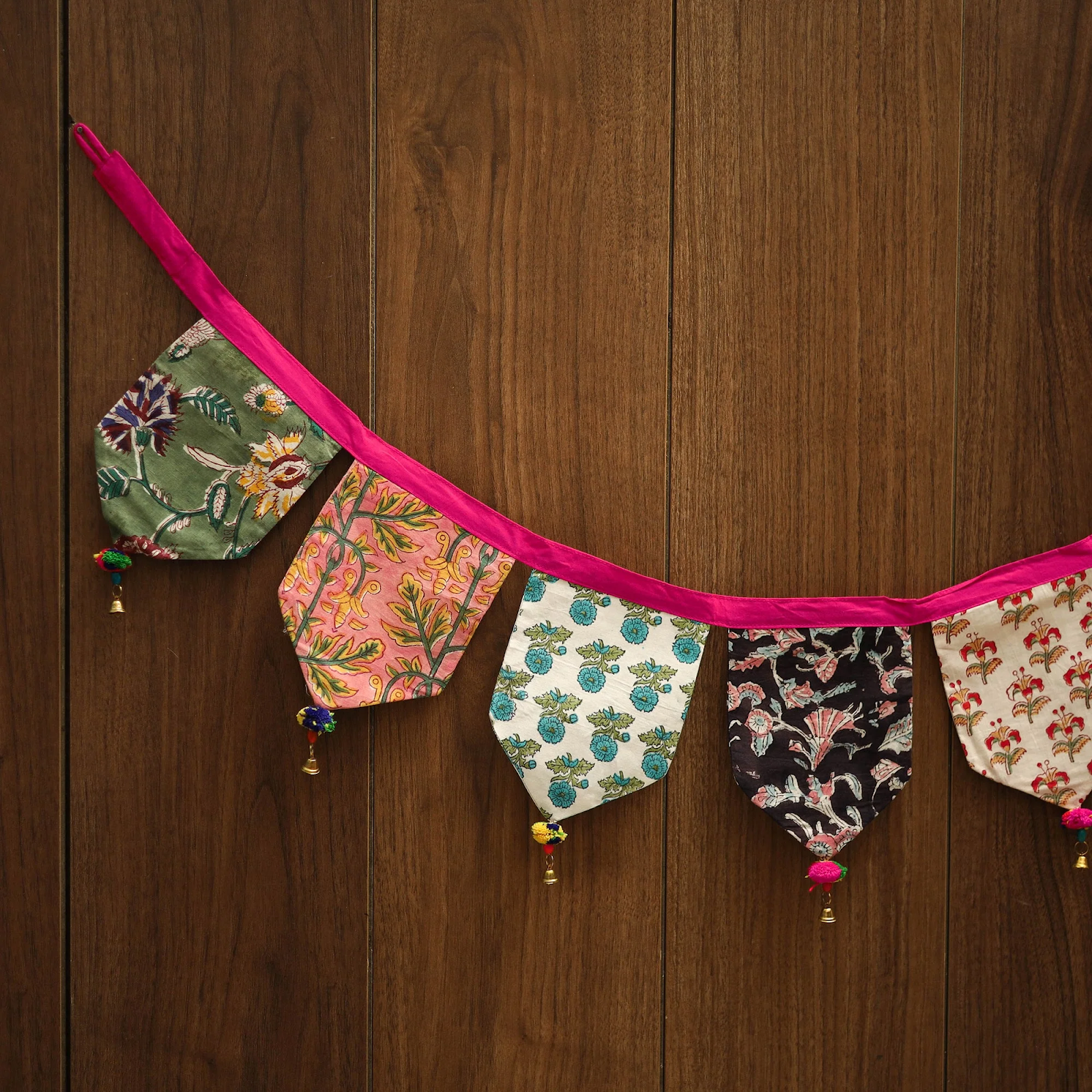 Colorful handmade fabric bunting banner with traditional floral patterns on wooden wall