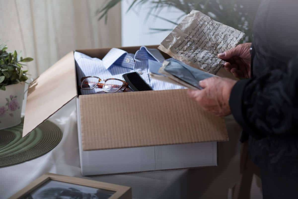 Person sorting old family photos and handwritten notes from a storage box at home