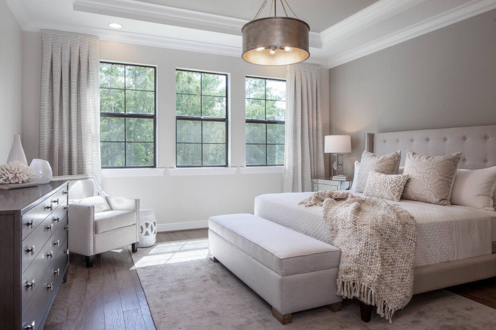 Modern neutral bedroom featuring upholstered bed, large windows, soft lighting, and minimalist decor