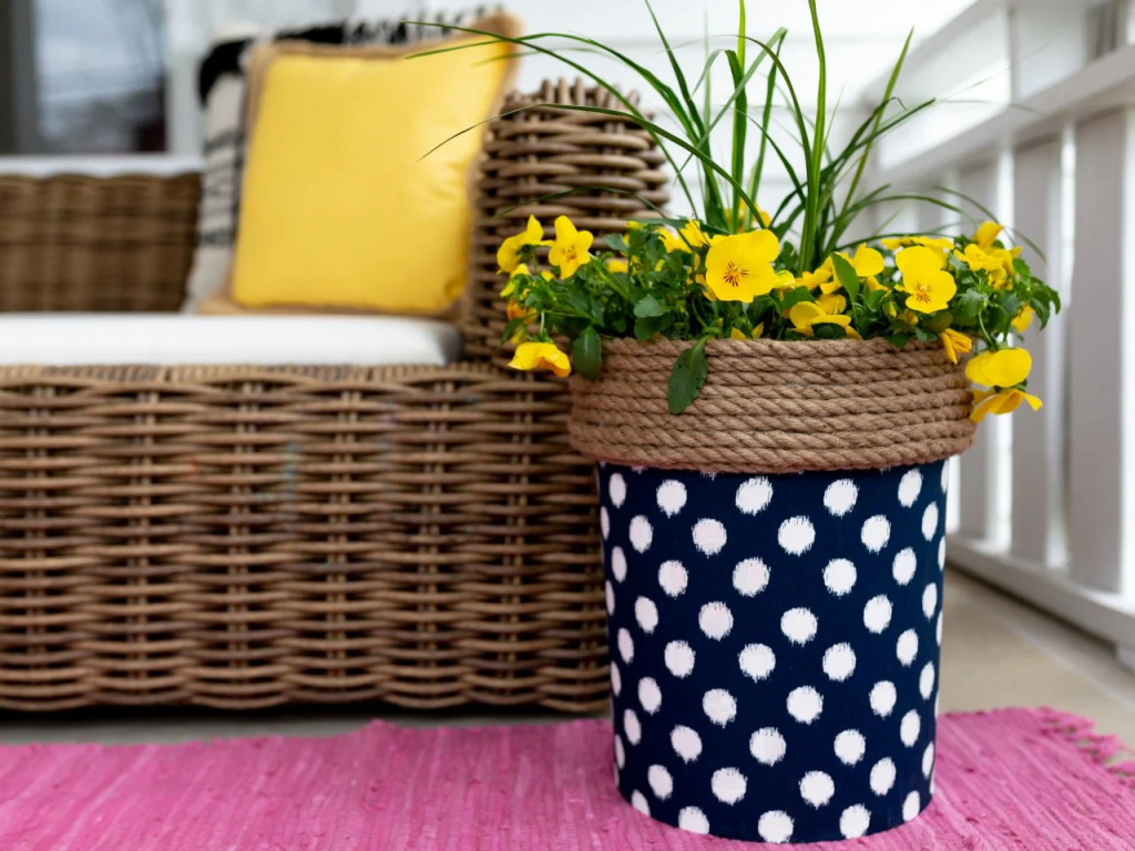 Upcycled bucket wrapped in a Blue and white polka dotted cover found new life as a happy little flower planter