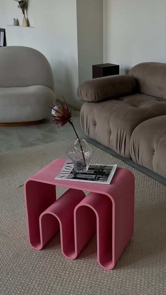 Modern living room with plush beige sofa, accent chair, and pink sculptural side table.